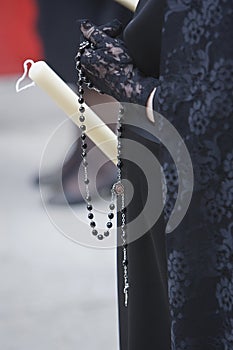 Detail of a woman dressed in mantilla holding a rosary and a candle during a Holy week procession photo