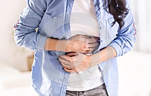 Detail of woman holding stomach by both hands in pain of abdominals