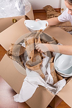 Detail of woman packaging fragile items using crumpled packing paper