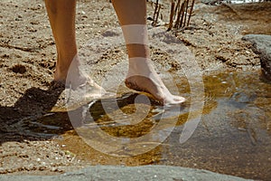 Detail of a woman's feet feeling the cool water of the river