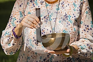 Detail of a woman`s hands holding and playing a Tibetan singing bowl