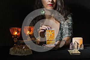 Detail of a woman`s hands showing a tarot card