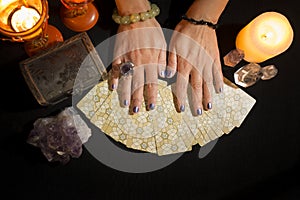 Detail of a woman`s hands on tarot cards on a black card table