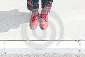 detail of woman& x27;s legs in chequered pants and red shoes