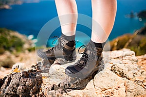 Detail of women legs in brown leather trekking shoes standing on rock