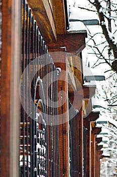 Detail of a wooden and black metal fence covered with snow during winter