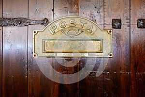 Detail of a wooden door with a letter box with the text Posta, letters in Spanish, in a retro style typical of rural areas