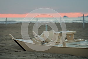 Detail of wooden oar boat half buried by the sand on the beach