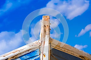 Detail of a wooden shipwreck with cloudy blue sky background.