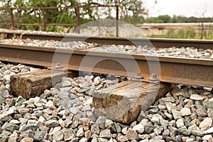 Detail of the wooden sleepers of the rails of a train track surrounded by boulders. Concept trains, tracks, transport, roads