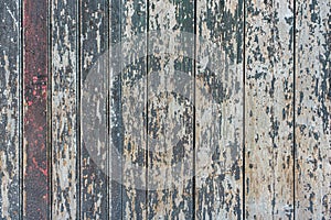 Detail of a wooden wall of a barn made of vertical, weathered boards with peeling green and red paint