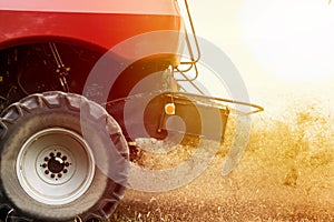 Detail of working red combine harvester; dust and straw pieces everywhere, harvester is working during harvest time