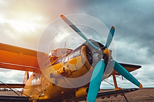 Detail of yellow biplane cabine, engine standing on airports at sunset