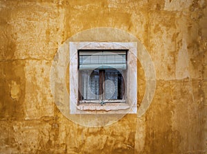 Detail of a yellow building facade, square homey window with green shutter and curtains, Cuenca