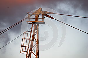 Detail of a yellow construction crane against cloudy sky at sunset in Belgrade