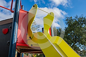 detail of a yellow and red slide in a playground in fall