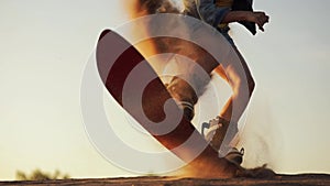 Detail a young beautiful girl hipster athlete in shorts tries doing tricks with a Board on sand dunes slow motion