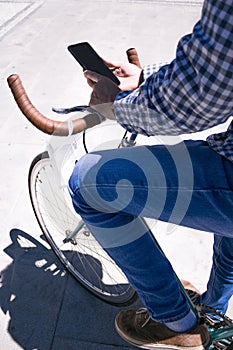 Detail of young man with mobile phone and fixed gear bicycle in the street