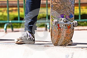 Detail of young man standing with his skateboard in a outdoor skate park