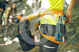 Detail of young man who preparing on a climb and standing a next to rock wall. Equipment for climbing on a man with copy space for