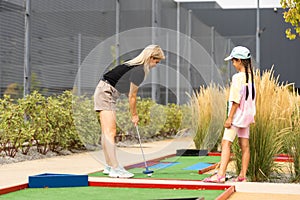 Detail of young woman and daughter playing mini adventure golf on a beautiful sunny summer day