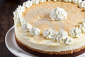 Detailed close-up of New York cheesecake with a dollop of whipped cream on top, focusing on the smooth cheesecake