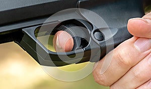 Detailed close-up of a persons index finger placed on the trigger of a black handgun, anonymous man ready to fire a simple sport