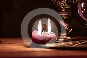 A detailed close-up shot of two lit pink candles with a dark, mystical background, emphasizing a ritualistic theme. photo