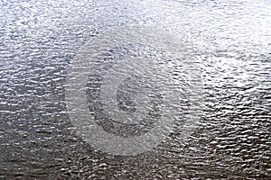 Detailed close up view on reflective water surface with waves and ripples taken at a lake