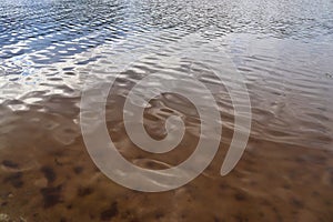 Detailed close up view on water surface with reflection sunlight at the waves and ripples