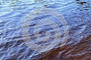 Detailed close up view on water surface with reflection sunlight at the waves and ripples