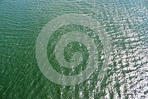 Detailed close up view on water surface with reflection sunlight at the waves and ripples