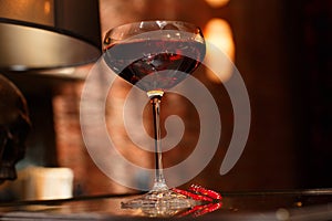 Detailed closed drink shot of a delicious fresh dark red cosmopolitan cocktail in a transparent glass standing on a table on a red