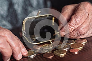 Detailed closeup photo of elderly 96 years old womans hands counting remaining coins from pension in her wallet after