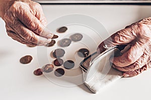 Detailed closeup photo of elderly 96 years old womans hands counting remaining coins from pension in her wallet after