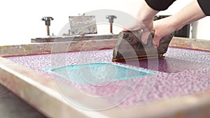 A detailed design is printed by hand with a squeegee and large silk-screen in different colors for sampeling