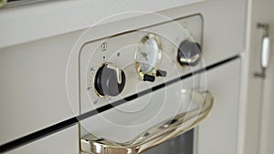 Detailed frame of woman's hand deftly operating temperature regulator, illuminating and extinguishing bright oven