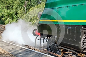 Detailed front view of a famous, British Steam Locomotive showing letting off steam while at a railway station. photo