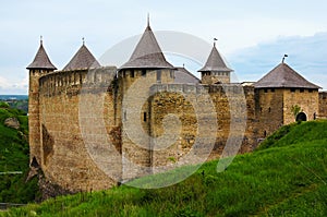Detailed landscape view of ancient castle. High stone walls and massive towers with tilled roofs against blue sky