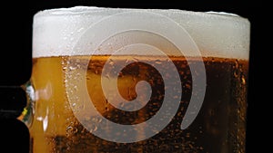 Detailed macro shot of gas bubbles and beer foam in mug. A glass of cold and tasty craft beer close up. Bubbles rise