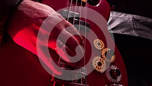 Detailed macro shot of male hands playing red bass guitar. Man touches strings with his fingers playing energetic melody