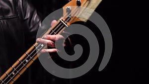 Detailed macro shot of male hands playing red bass guitar. Man touches strings with his fingers playing energetic melody