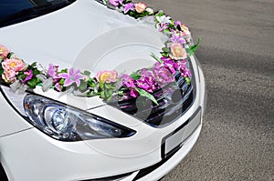 A detailed photo of the hood of the wedding car, decorated with many different flowers. The car is prepared for a wedding ceremon