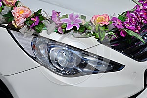 A detailed photo of the hood of the wedding car, decorated with many different flowers. The car is prepared for a wedding ceremon