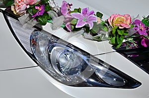 A detailed photo of the hood of the wedding car, decorated with many different flowers. The car is prepared for a wedding ceremon