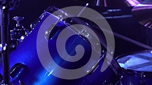 Detailed shot of a drum set on stage. neon blue stage lights fill the room