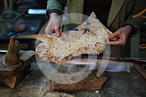 The detailed surface of the wood is inspected closely, showcasing the value placed on unique wood grains in the art of