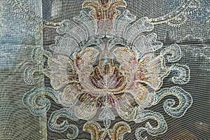 Detailed texture of an antique lace curtain hanging in a window