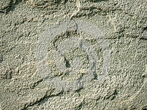 Detailed texture of rough green stone wall under sunlight, abstract natural background for construction, design or 3D