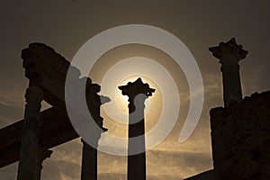 Detailed view from below of the capitals, cornice and columns of the Roman theater in Merida, with the backlit sunlight at sunset